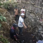 Plengsengan batu yang ambrol di tepi saluran air berlumpur di permukiman lereng Kota Batu
