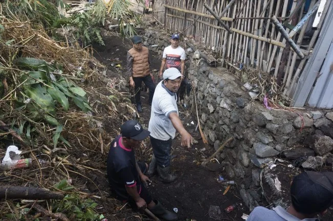 Plengsengan batu yang ambrol di tepi saluran air berlumpur di permukiman lereng Kota Batu