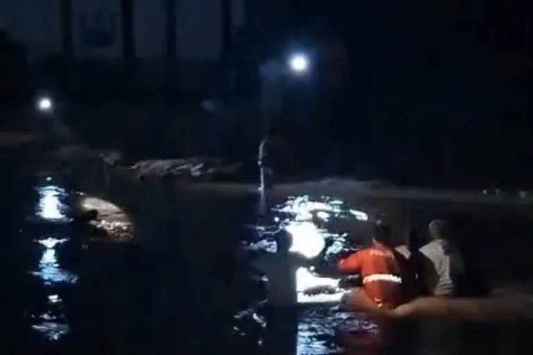 Ilustrasi permukiman tergenang banjir di tepi sungai dengan tanggul karung pasir yang terkikis arus