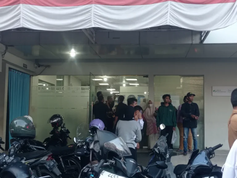 Ilustrasi lorong IGD rumah sakit yang padat dengan ranjang pasien dan ambulans bersiaga di luar pada malam hari