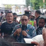 Ilustrasi pendapa kantor bupati dengan bingkai foto kosong di dinding dan spanduk aksi di halaman