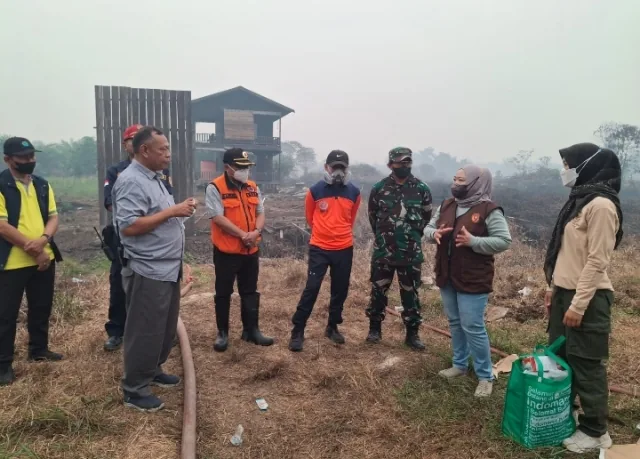 Asap tebal dan langit kekuningan menyelimuti jalan di kawasan lahan gambut yang terbakar