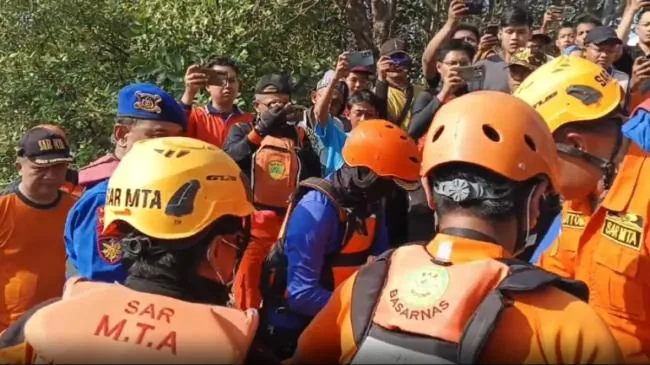 Sungai payau berarus deras saat air pasang di tepi hutan bakau, dengan joran pancing tergeletak di tepian
