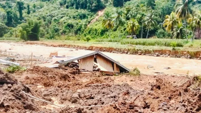 Permukiman di tepi sungai yang terendam banjir dengan material longsor menutup sebagian jalan